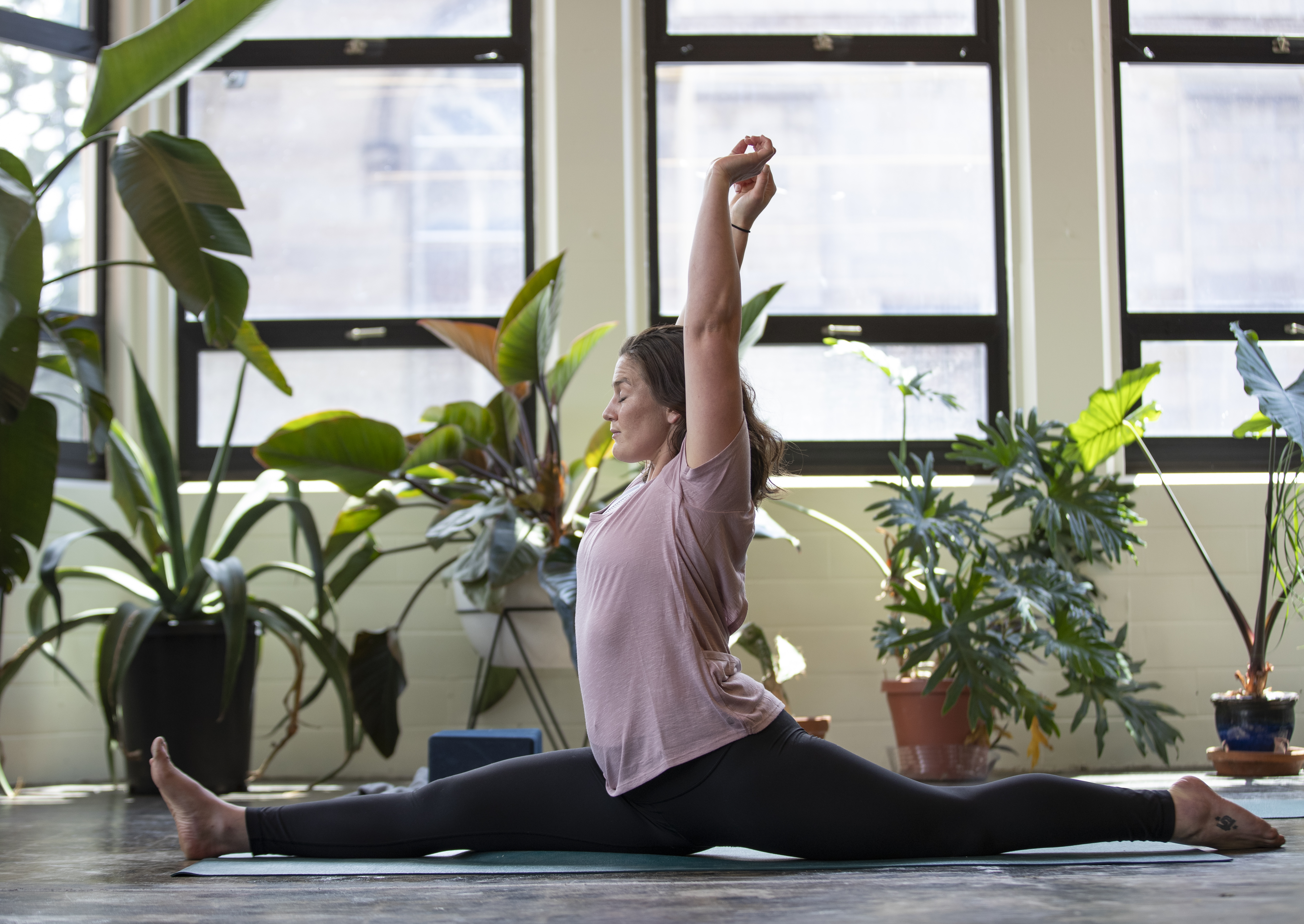 Elly performing the splits in a plant-filled yoga studio in Denver